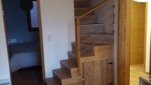 Una sala de estar moderna con una escalera de madera, un sofá gris y piso de madera.