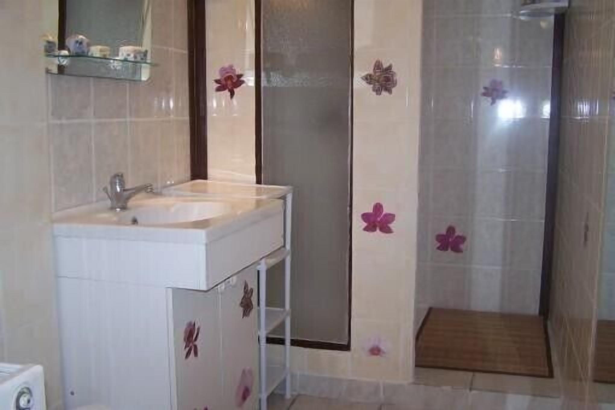 Un baño con lavamanos, espejo y zona de ducha.