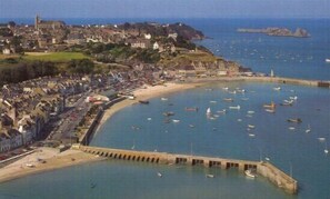 Une ville côtière dotée d’un port de plaisance rempli de bateaux, d’une plage de sable et de bâtiments historiques.