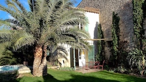 A house with a stone exterior, a small pool, and a patio with outdoor furniture.
