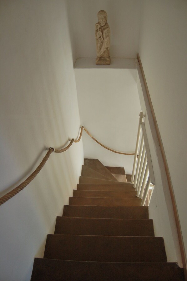 A staircase with a rope barrier, white walls, and a statue at the top.
