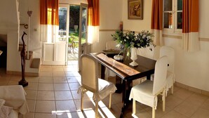 A dining area with a wooden table, white chairs, a vase of flowers, and a painting on the wall.
