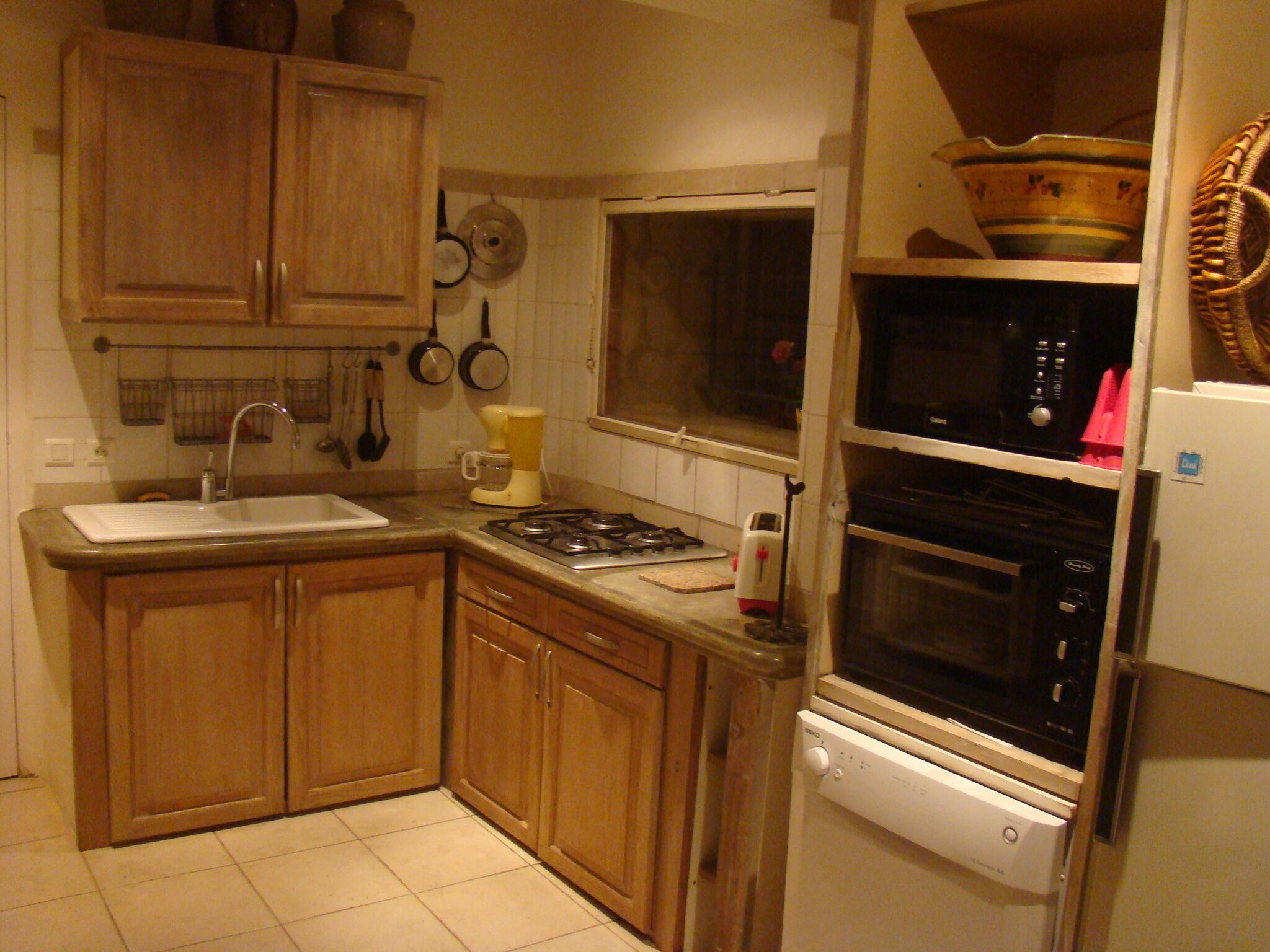 A compact kitchen with wooden cabinets, a sink, a stove, a microwave, and a dishwasher.