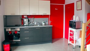 Una cocina moderna con armarios grises, una pared de acento roja, una cafetera y un microondas.