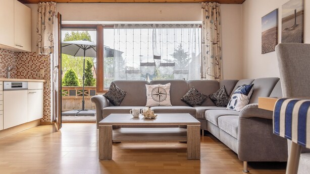 A living room with a sofa, coffee table, and a view of the outdoors. - Spacious and bright: the first floor apartment with its spacious bathroom is equipped with a (Carolinensiel)