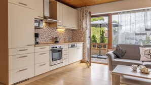 A modern kitchen with white cabinets, a built-in oven, and a microwave. - Spacious and bright: the first floor apartment with its spacious bathroom is equipped with a (Carolinensiel)