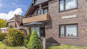 A two-story brick building with a balcony, a sign reading 'Haus Wasserkant,' and a well-maintained garden. - Spacious and bright: the first floor apartment with its spacious bathroom is equipped with a (Carolinensiel)