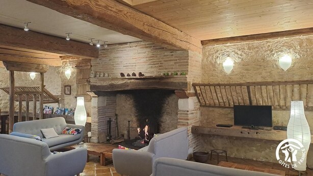 A cozy living room with a stone fireplace, comfortable seating, and a television.