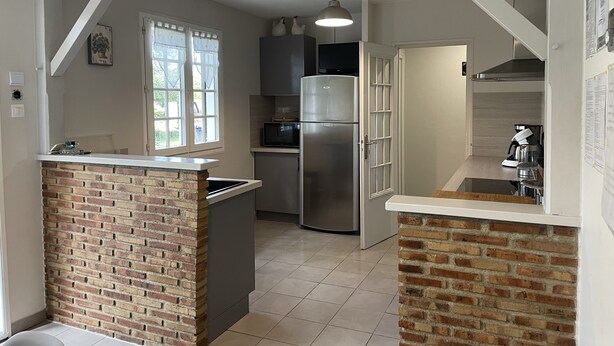 Una cocina con pared de ladrillo decorativa, electrodomésticos de acero inoxidable y encimera blanca.