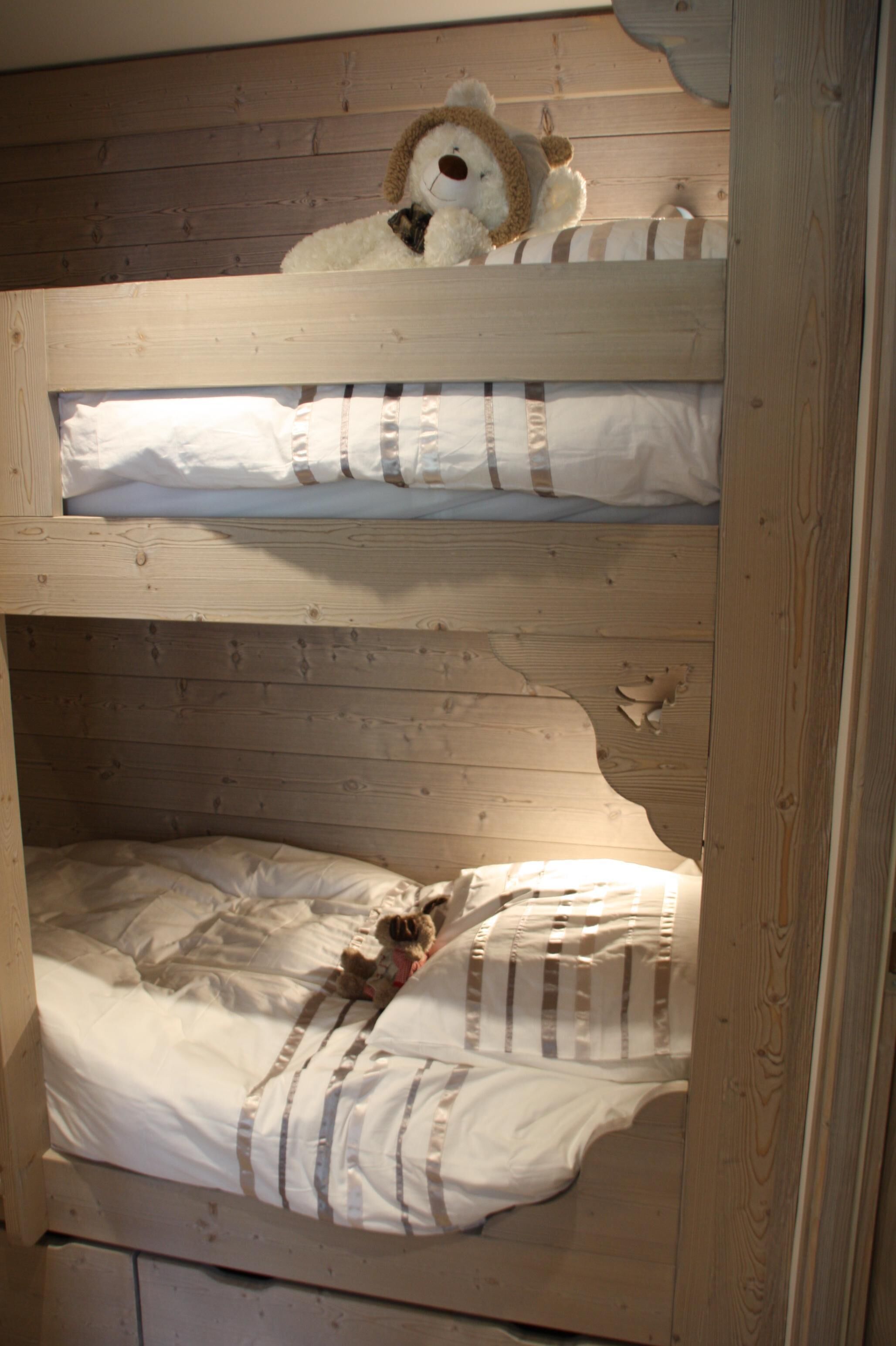 Un letto a castello con due letti, ognuno con un cuscino e un peluche.
