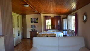 A room with a wooden ceiling, a white sofa, a dining table with chairs, and a cabinet with glass doors. - Chalet between sea and scrub  (Coggia)