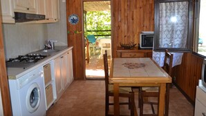 A compact kitchen with a washing machine, a stove, and a dining table with chairs. - Chalet between sea and scrub  (Coggia)