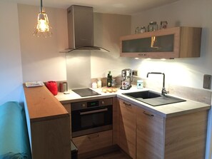 Eine kompakte Küche mit Backofen, Kochfeld, Spüle und Holzschränken.