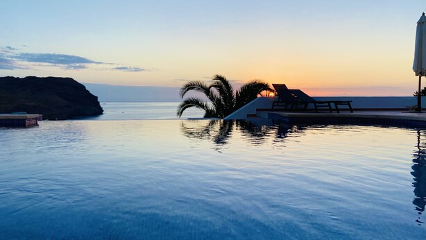 A serene infinity pool with a sunset view, palm trees, and lounge chairs. - Ranked among the 21 most pleasant villas in Andalusia by the TIMES in 2023 (Las Negras)