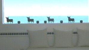 A window with bull silhouettes and decorative cups on a white sofa with patterned pillows. - Ranked among the 21 most pleasant villas in Andalusia by the TIMES in 2023 (Las Negras)