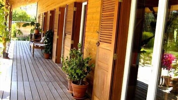 A wooden porch with potted plants and sliding doors.