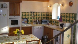 A kitchen with wooden cabinets, a built-in oven, a microwave, a toaster, and a sink. - Traditional Provencal gite, offering quietness and serenity (Mazan)