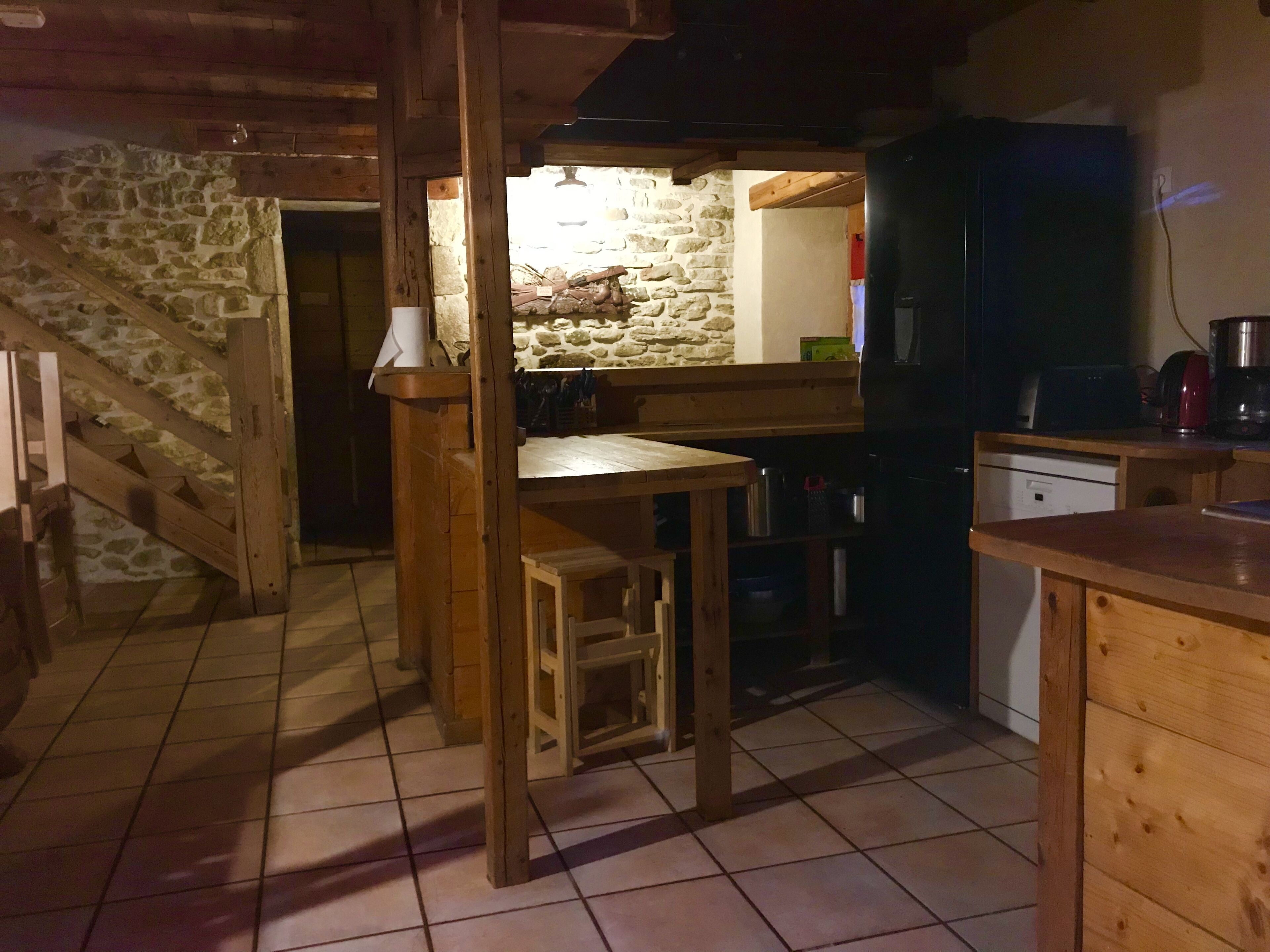Une cuisine rustique avec des poutres en bois, un mur en pierre et un sol carrelé.