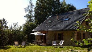 Una casa rústica con techo inclinado y un pequeño patio con mobiliario exterior.