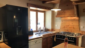 Una cocina compacta con un refrigerador negro, un lavavajillas empotrado, una estufa y una encimera de madera.