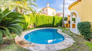 A swimming pool surrounded by lush greenery and a building with a tiled roof. - Oliva Nova Golf pool, private garden, ADSL-Wifi, TV SAT and offerts 2013 (Oliva)