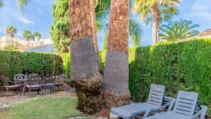 A garden with two lounge chairs, a stone pathway, and a hedge. - Oliva Nova Golf pool, private garden, ADSL-Wifi, TV SAT and offerts 2013 (Oliva)