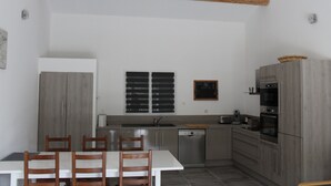 A modern kitchen with a dining table and chairs, a built-in oven, and a dishwasher.