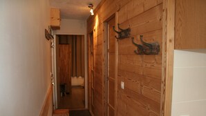 A wooden hallway with a door on the right and a small stool in the center. - Roc de Peclet apartment 41 m², South, Foot of the slopes, Heart Station (Les Belleville)