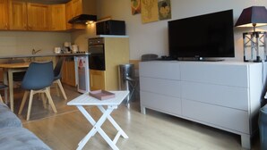 A compact living space with a kitchenette, a dining area, a TV, and a small table. - Roc de Peclet apartment 41 m², South, Foot of the slopes, Heart Station (Les Belleville)