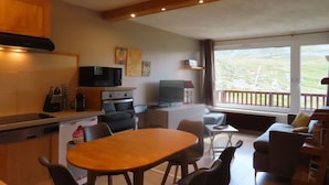 A modern kitchen with a dining area, a television, and a view of the outdoors. - Roc de Peclet apartment 41 m², South, Foot of the slopes, Heart Station (Les Belleville)