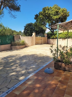 Une terrasse avec un sol en pierre, une clôture en bois et une structure en forme de pergola.