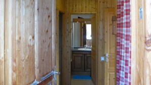 A wooden interior hallway with a bathroom visible in the background, including a sink and mirror. - Appart 7 pers au ski, 3*, Saint Jean d'Arves - Les Sybelles - Swimming pool (Saint jean d'arves)