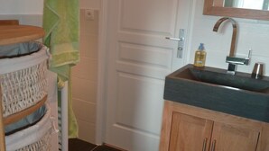 Ein Badezimmer mit Holzschrank, Waschbecken und Spiegel. Ein Handtuchhalter mit einem grünen Handtuch.