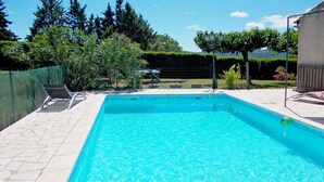 Una piscina rectangular con agua azul cristalina, rodeada por un solárium con baldosas.