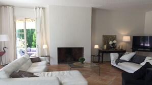 Uma sala de estar com um sofá branco, um sofá preto, uma mesa de centro de vidro e uma lareira.