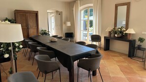 Uma sala de jantar com uma mesa comprida, cadeiras, um armário de madeira e um espelho grande.