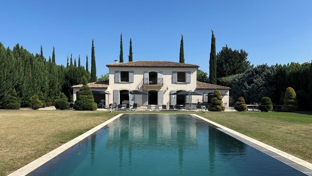 Uma casa de dois andares com piscina na frente.