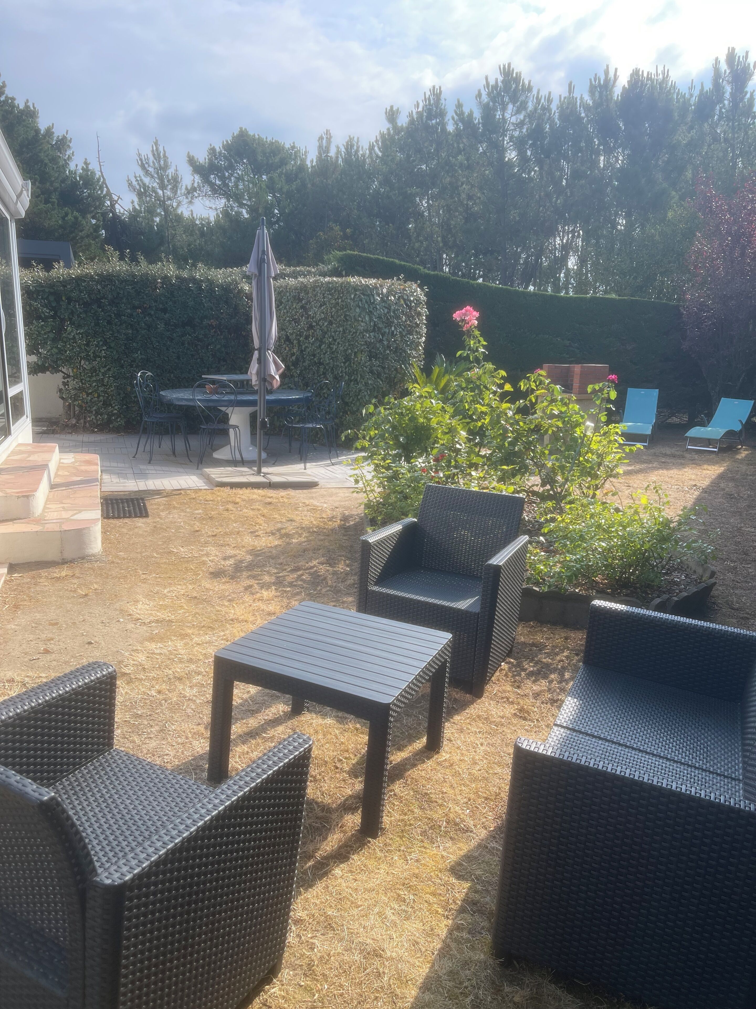 Ein möblierter Patio mit Korbmöbeln, einem Tisch und Stühlen.