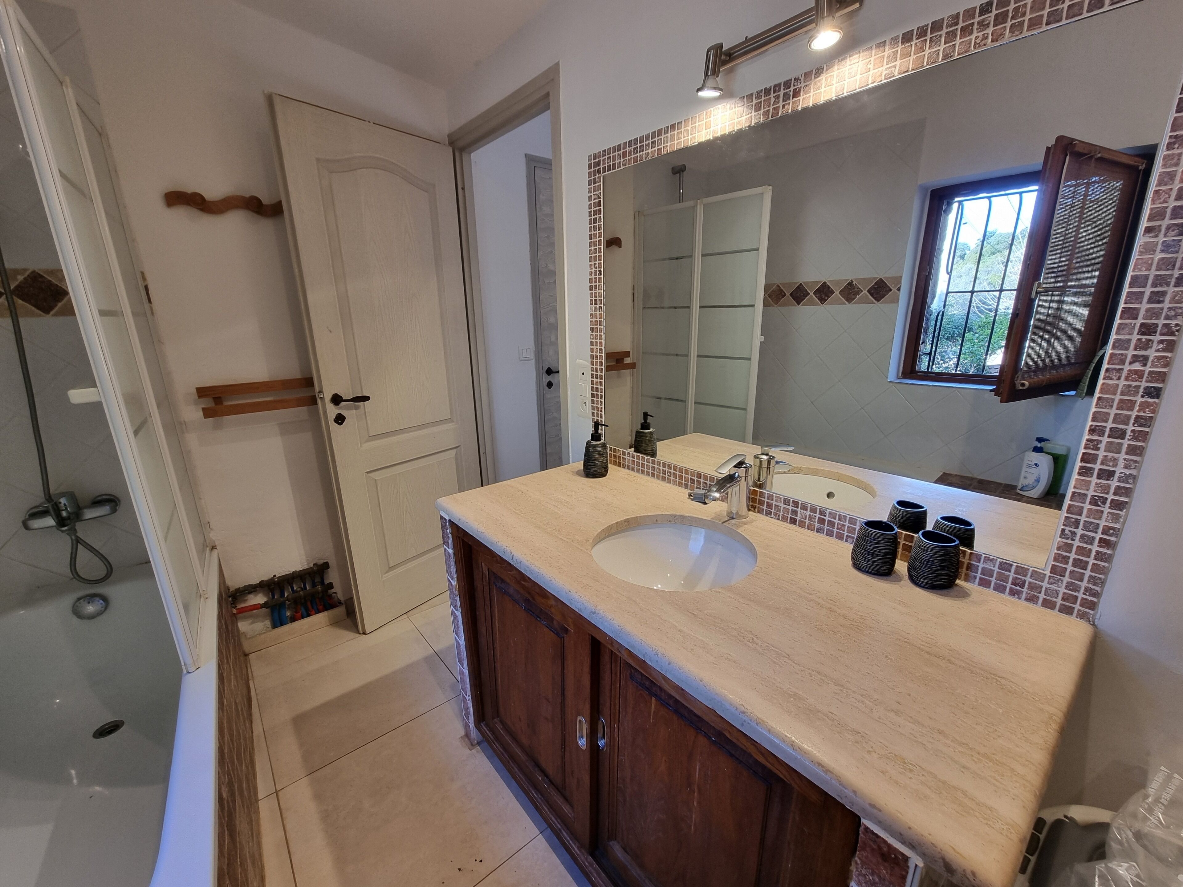 A bathroom with a sink, mirror, and shower.