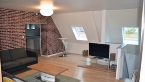 A modern living room with a brick wall, a fireplace, a flat-screen TV, and a sofa. - Contemporary house 10 people with sauna and Spa (Kaysersberg Vignoble)