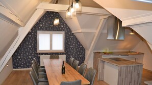 A dining area with a wooden table and chairs, a window with blinds, and a kitchen area with a wooden countertop and cabinets. - Contemporary house 10 people with sauna and Spa (Kaysersberg Vignoble)