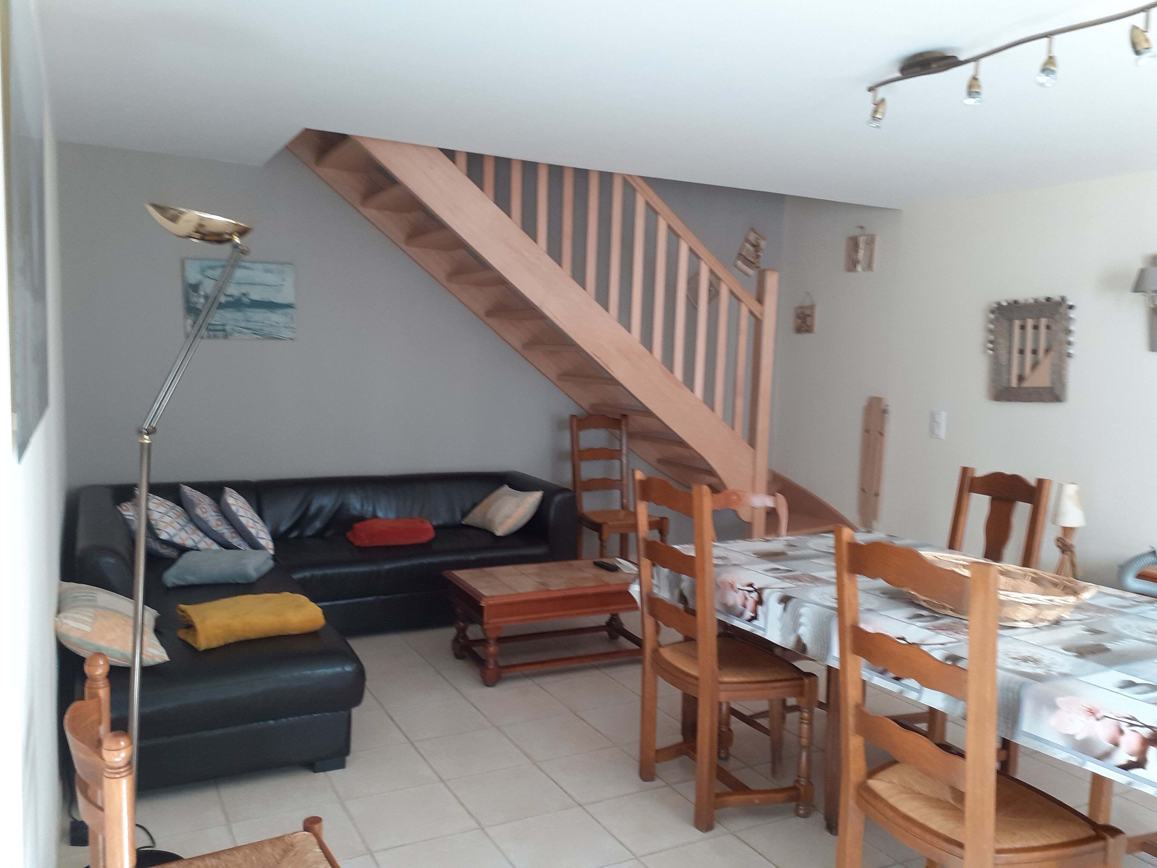 Ein Wohnzimmer mit einer schwarzen Couch, einem Holzesstisch und einer Treppe.