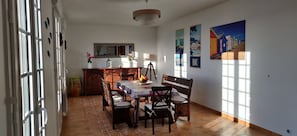 Un comedor con una mesa dispuesta para cuatro personas, un banco y un espejo sobre la mesa.