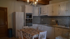 Une cuisine compacte avec des meubles blancs, un four encastré et une table à manger avec des chaises.