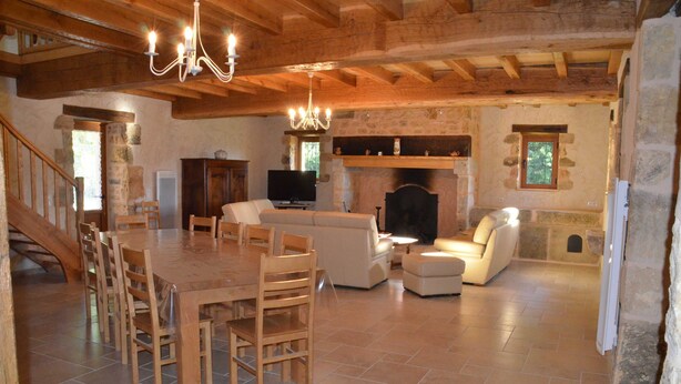 Un vaste espace de vie comprenant une table à manger en bois, des chaises, un canapé et une cheminée.