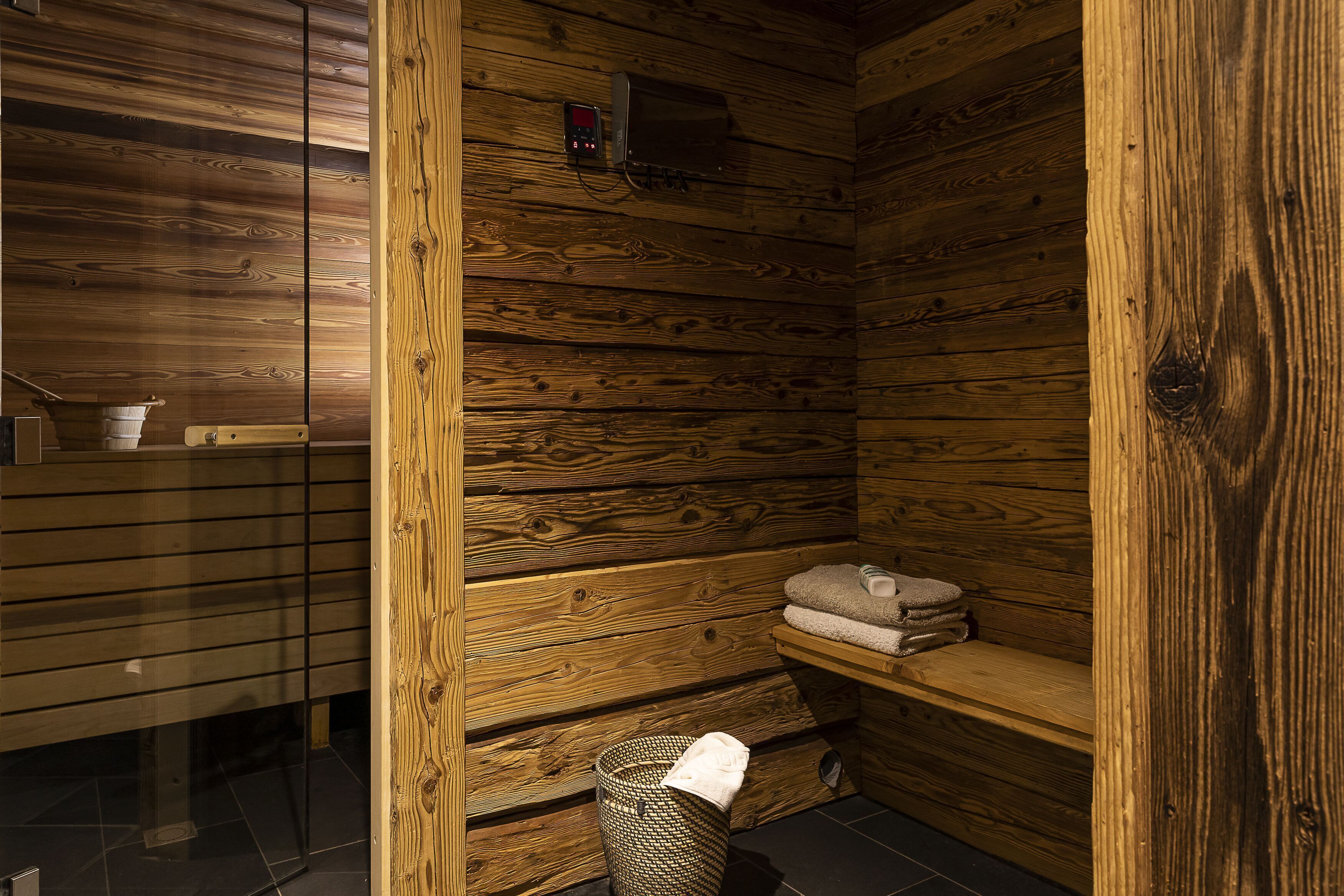 Een houten cabin met sauna, een plank met handdoeken en een kleine verwarming.