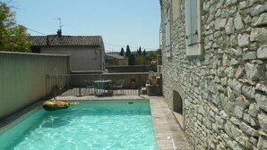 Una piscina con un muro in pietra e un edificio sullo sfondo.