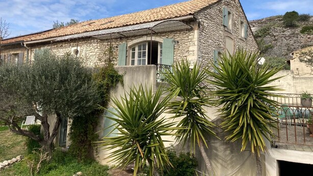 A stone house with a tiled roof, a small balcony, and a garden with palm trees. - Stone farmhouse with swimming pool between Avignon and Orange, in Roquemaure (Roquemaure)