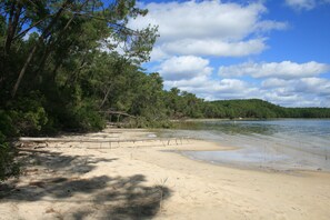 A beach with sand, trees, and a body of water. - House on Lake Hourtin: largest natural freshwater lake in France (Hourtin)