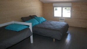 Una habitación con cama, ventana y paredes de madera.